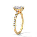 Oval engagement ring in yellow gold with pavé diamond band and cathedral-set oval center stone