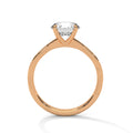 Gold solitaire ring with clear gemstone in prong setting and slim round band